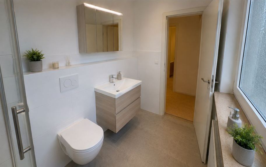 Gäste-WC mit Waschtisch in hellem Holz und Pflanze am Fenster